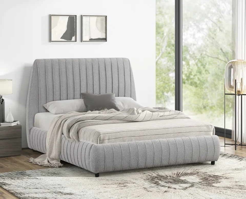 Channel-tufted grey upholstered bed in a bright bedroom with tall windows